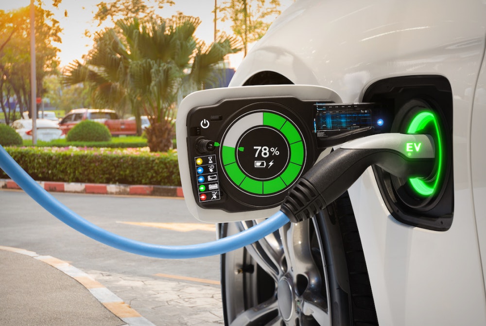 Close-up of Tesla charging port with charging connector plugged in, symbolizing battery cell balancing.